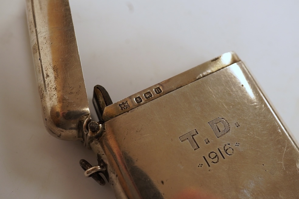 A George V silver mounted rectangular cigarette box, with later engraved inscription, Birmingham, 1932, 13.7cm, together with a similar silver vesta case and two modern silver wine labels. Condition - poor to fair